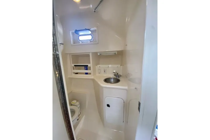 Slide: The Image of 1996 Pursuit 3000 Offshore boat bathroom with sink, toilet, and storage shelves. - 15