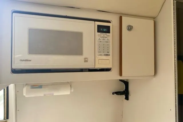 Slide: The Image of Microwave and cabinet inside a 1996 Pursuit 3000 Offshore boat kitchen area. - 12