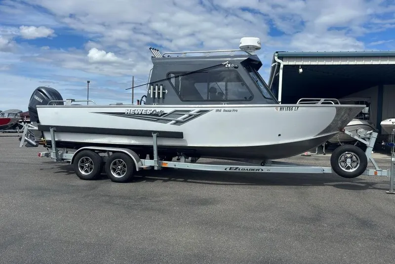The Image of 2024 Hewescraft 240 Ocean Pro Hardtop boat on trailer, parked outdoors under cloudy sky. - 1