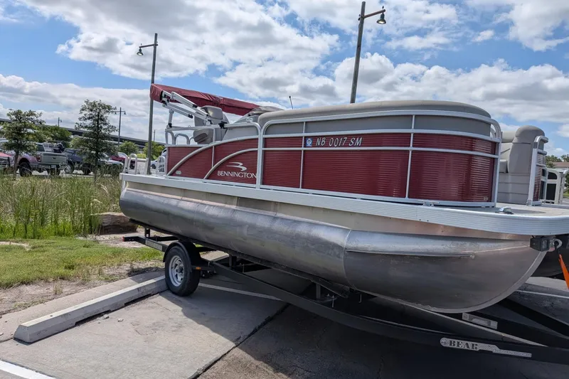 The Image of 2021 Bennington 205SL pontoon boat on trailer, parked outdoors under a cloudy sky. - 1
