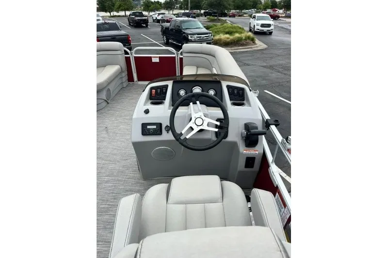 Slide: The Image of 2021 Bennington 205SL boat interior with steering wheel and seating in a parking lot. - 9