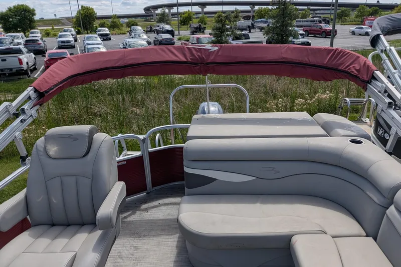 Slide: The Image of 2021 Bennington 205SL pontoon boat with gray seating and red canopy in a parking lot. - 3