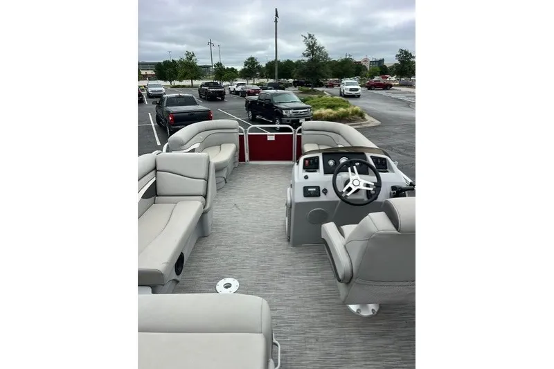 Slide: The Image of 2021 Bennington 205SL pontoon boat interior with seating and steering wheel in parking lot. - 8