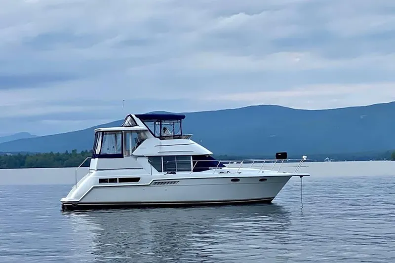 Slide: The Image of 1997 Carver 355 Aft Cabin Motor Yacht on serene lake with mountain backdrop. - 2