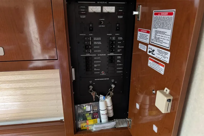 Slide: The Image of Electrical panel inside a 2010 Sea Ray Sundancer 310 boat, featuring switches and safety warnings. - 26