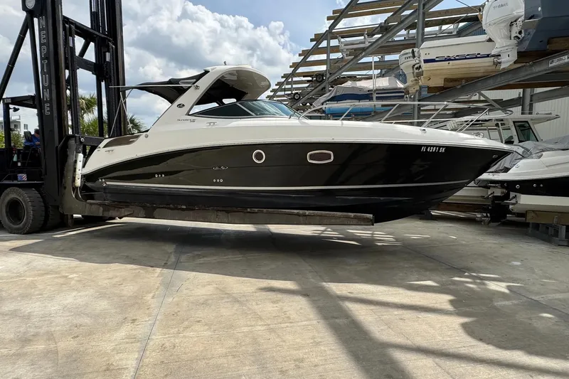 The Image of 2010 Sea Ray Sundancer 310 boat lifted by forklift in marina storage. - 1