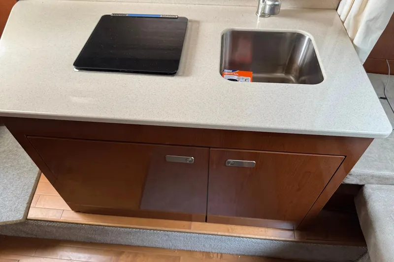 Slide: The Image of Compact kitchen area in a 2010 Sea Ray Sundancer 310 yacht, featuring a sink and stove. - 33