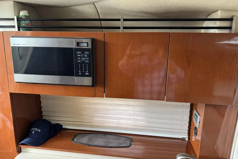 Slide: The Image of 2010 Sea Ray Sundancer 310 interior with microwave and wooden cabinetry. - 28