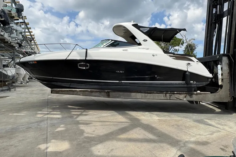 Slide: The Image of 2010 Sea Ray Sundancer 310 boat lifted on a forklift under a cloudy sky. - 3