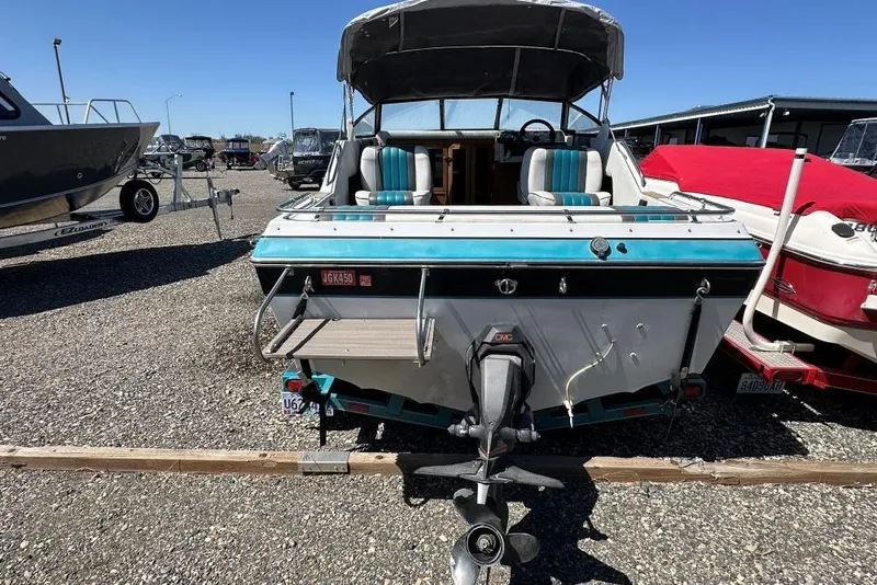 Slide: The Image of 1992 Reinell 192 RM boat with outboard motor, parked in a gravel lot. - 4