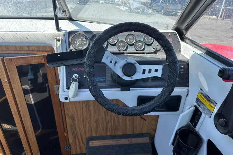 Slide: The Image of Steering wheel and dashboard of a 1992 Reinell 192 RM boat, featuring gauges and wood accents. - 6
