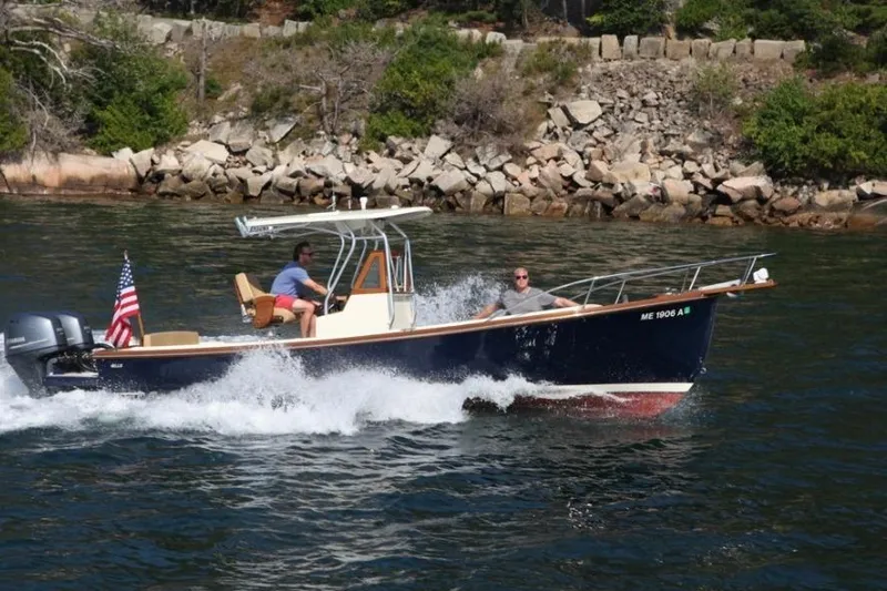 Slide: The Image of 1988 Bunker and Ellis 24 Open boat cruising near rocky shoreline with American flag. - 4