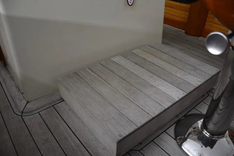 Slide: The Image of Wooden deck step on 1988 Bunker and Ellis 24 Open boat, featuring polished metal elements. - 25