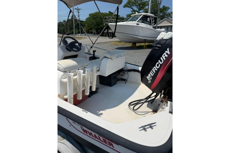 Slide: The Image of 2003 Boston Whaler 130 Super Sport boat with Mercury engine, featuring seating and rod holders. - 8