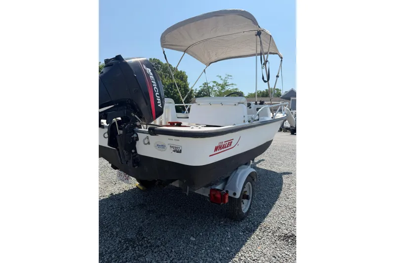 Slide: The Image of 2003 Boston Whaler 130 Super Sport boat with Mercury engine and canopy on trailer. - 9
