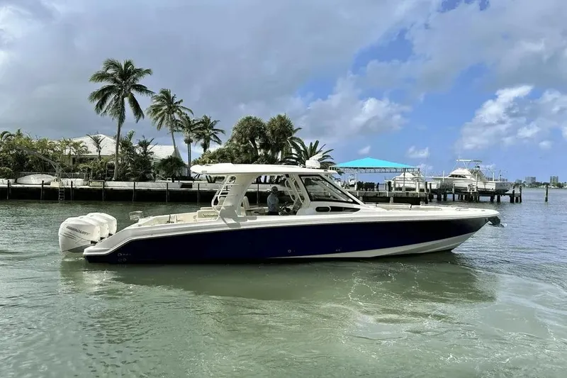 The Image of 2019 Boston Whaler 350 Realm boat on water, with palm trees and docks in the background. - 1