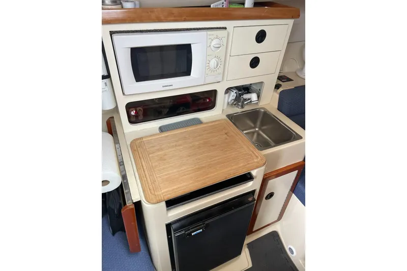 Slide: The Image of 2003 Albin 28 Tournament Express galley with microwave, sink, and compact fridge. - 13