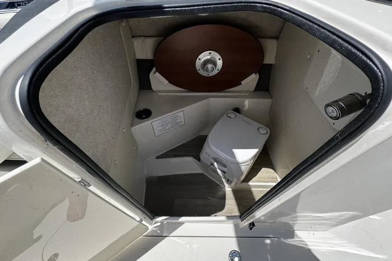 Slide: The Image of 2022 Stingray 212 SC boat interior with portable toilet and storage space. - 16