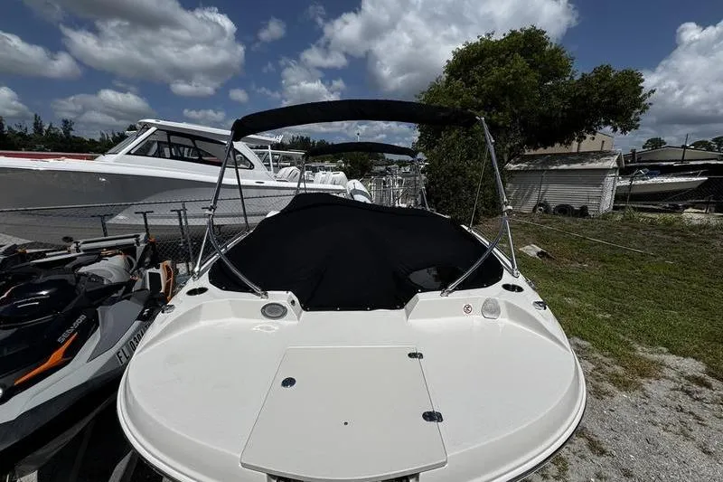 Slide: The Image of 2022 Stingray 212 SC boat with canopy, parked outdoors under a cloudy sky. - 3