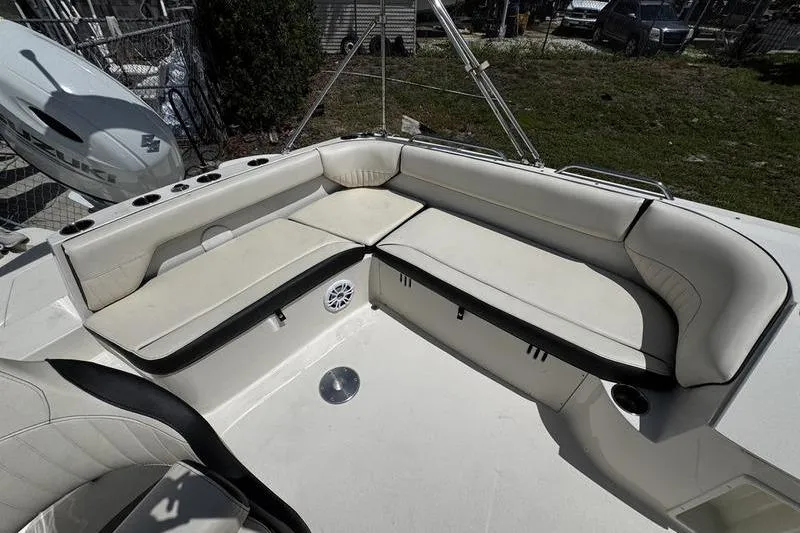 Slide: The Image of 2022 Stingray 212 SC boat interior with white cushioned seating and cup holders. - 23