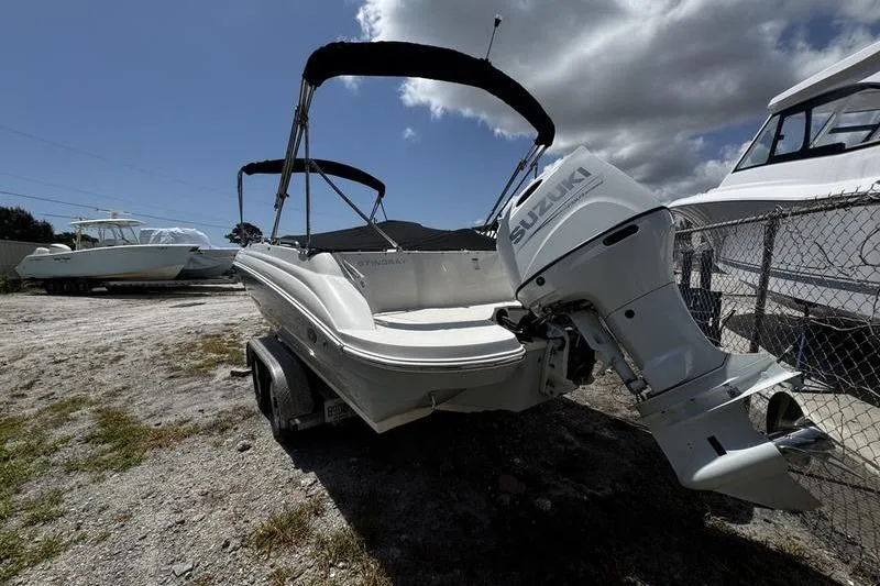 Slide: The Image of 2022 Stingray 212 SC boat with Suzuki outboard motor on a trailer, parked outdoors. - 6