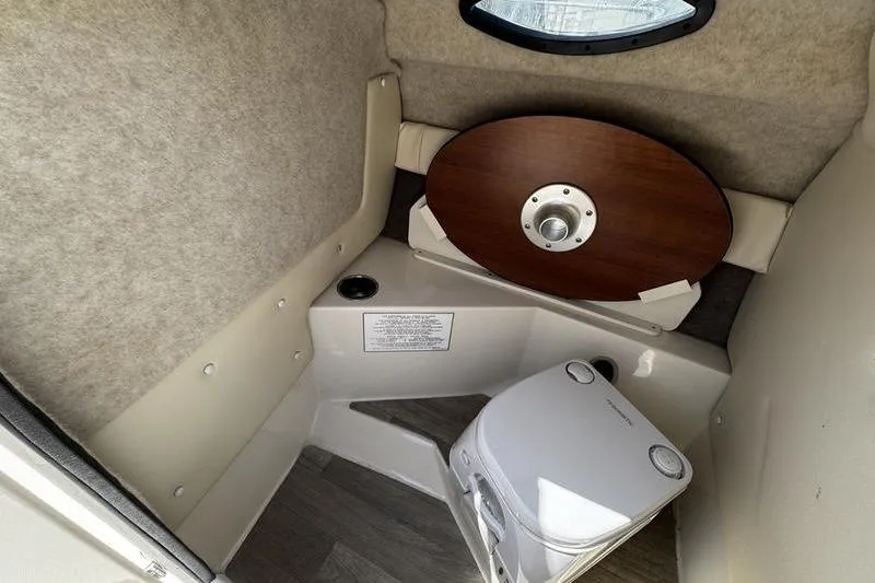 Slide: The Image of 2022 Stingray 212 SC boat interior with compact toilet and wooden table. - 17