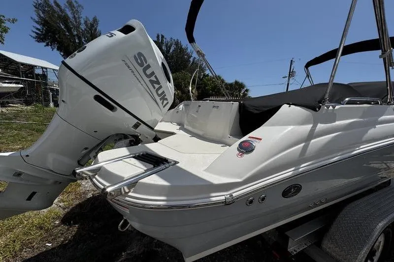 Slide: The Image of 2022 Stingray 212 SC boat with Suzuki outboard motor, parked on a trailer. - 7