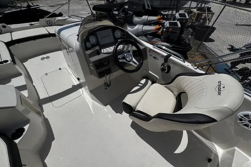 Slide: The Image of 2022 Stingray 212 SC boat interior with steering wheel and comfortable seating. - 19