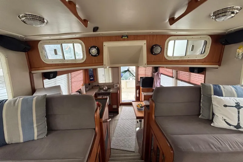 Slide: The Image of Interior of a 2004 Nordic Tug 37, featuring cozy seating and a compact kitchen area. - 21