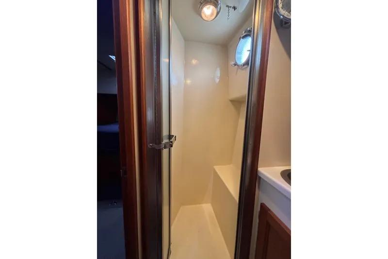 Slide: The Image of Shower area in 2004 Nordic Tug 37 boat with porthole and wooden door. - 16