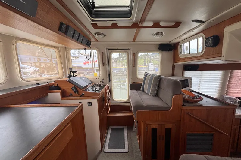 Slide: The Image of Interior of a 2004 Nordic Tug 37, featuring a cozy helm and seating area. - 12