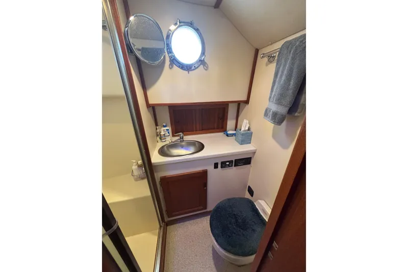 Slide: The Image of Bathroom interior of 2004 Nordic Tug 37 with sink, mirror, and porthole window. - 15