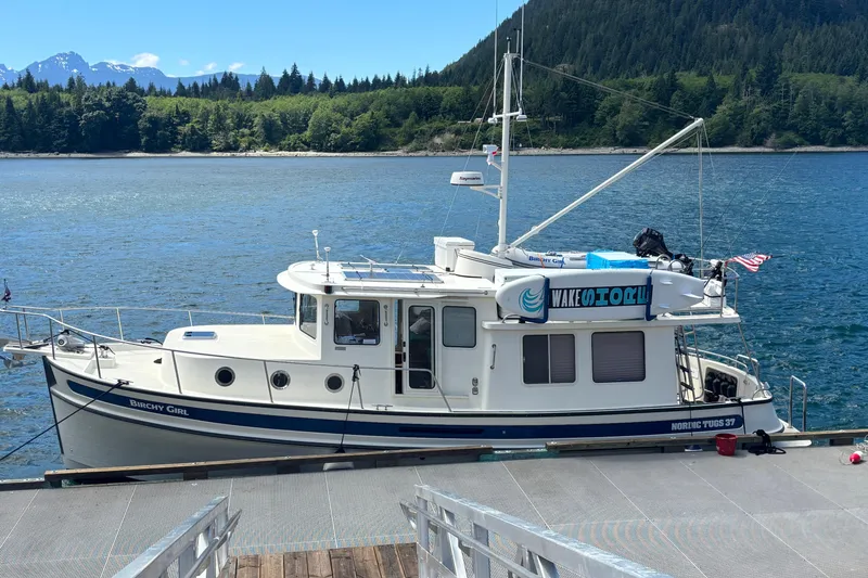 Slide: The Image of 2004 Nordic Tug 37 docked by scenic forested shoreline and mountains. - 1