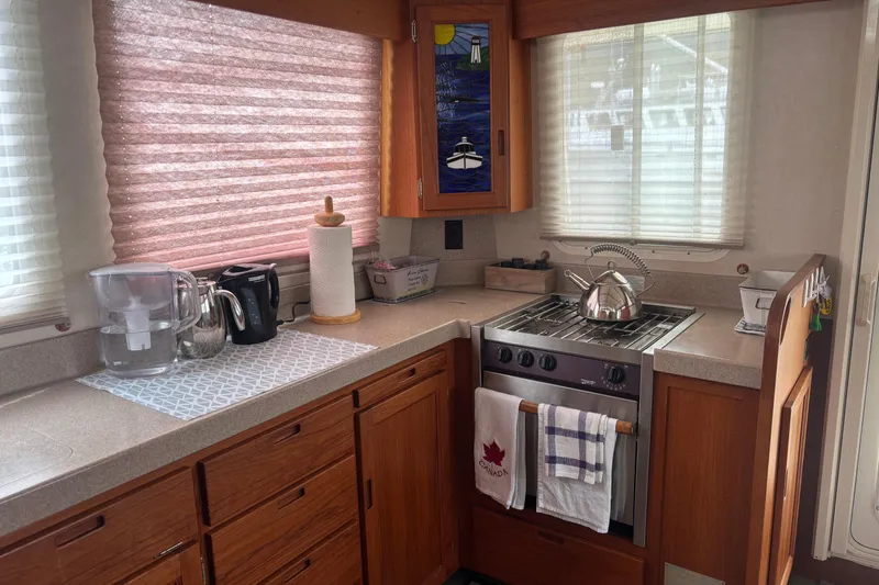Slide: The Image of Cozy kitchen in a 2004 Nordic Tug 37 boat with stove, kettle, and wooden cabinetry. - 10