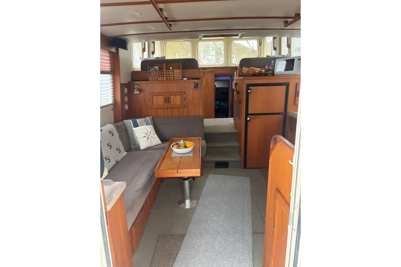 Slide: The Image of Cozy interior of a 2004 Nordic Tug 37 with wooden furnishings and seating area. - 8