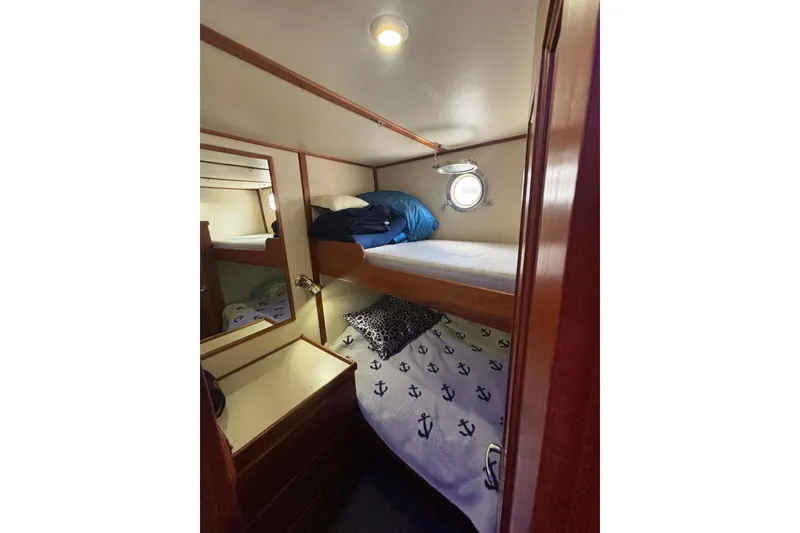 Slide: The Image of Cozy cabin with bunk beds in 2004 Nordic Tug 37, featuring nautical-themed bedding. - 13