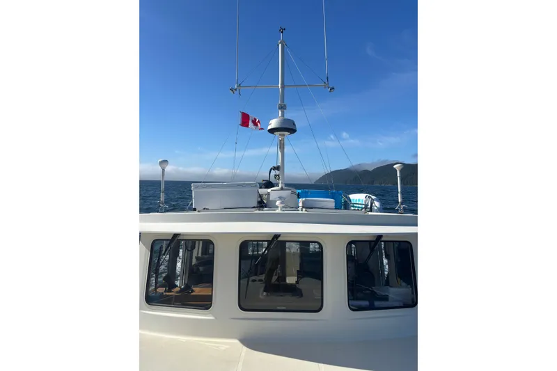 Slide: The Image of Nordic Tug 37 (2004) cruising with Canadian flag, ocean and mountains in background. - 2