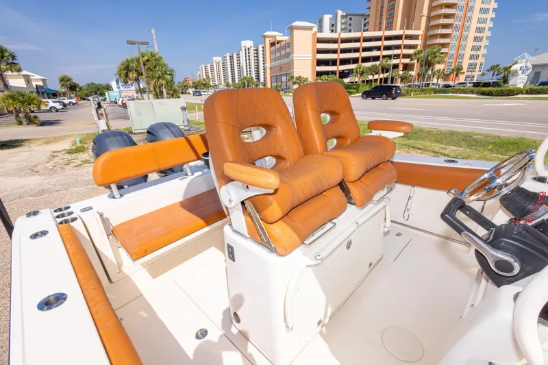 Slide: The Image of 2017 Cobia 261 Center Console boat with tan seating, parked near a coastal road. - 39