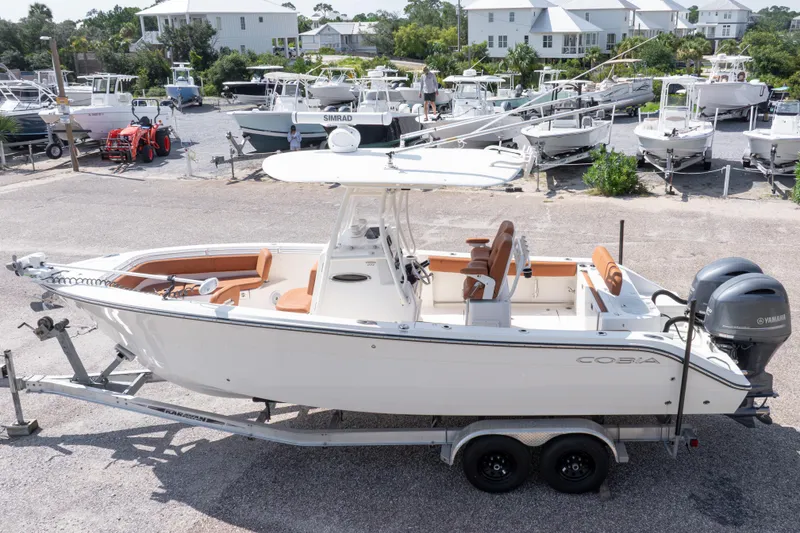 Slide: The Image of 2017 Cobia 261 Center Console boat on trailer, parked in a marina with other boats. - 3