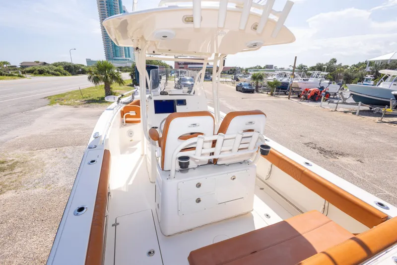 Slide: The Image of 2017 Cobia 261 Center Console boat with tan seating, docked near a coastal road. - 19
