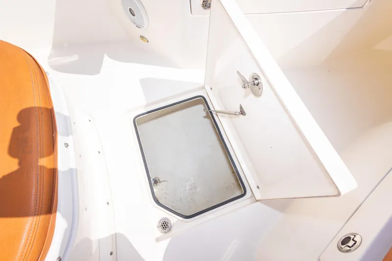 Slide: The Image of 2017 Cobia 261 Center Console boat storage compartment with open hatch and seating. - 35