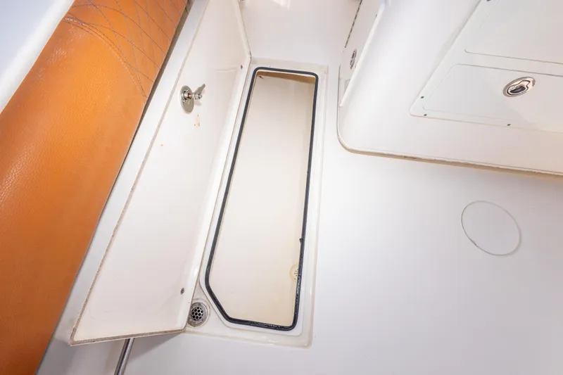 Slide: The Image of 2017 Cobia 261 Center Console storage compartment with tan cushion and white interior. - 44