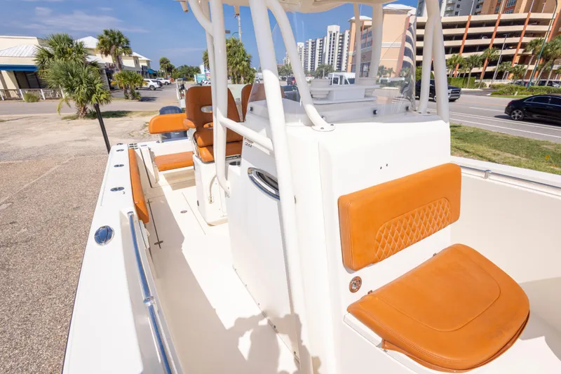 Slide: The Image of 2017 Cobia 261 Center Console boat with tan seating, docked near a coastal road. - 38