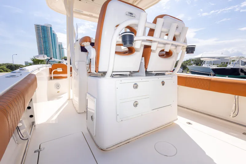 Slide: The Image of 2017 Cobia 261 Center Console boat interior with seating and storage, docked near modern buildings. - 43