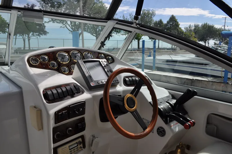 Slide: The Image of The image shows the helm of a 1999 Doral 350sc boat with a wooden steering wheel and instruments. - 6