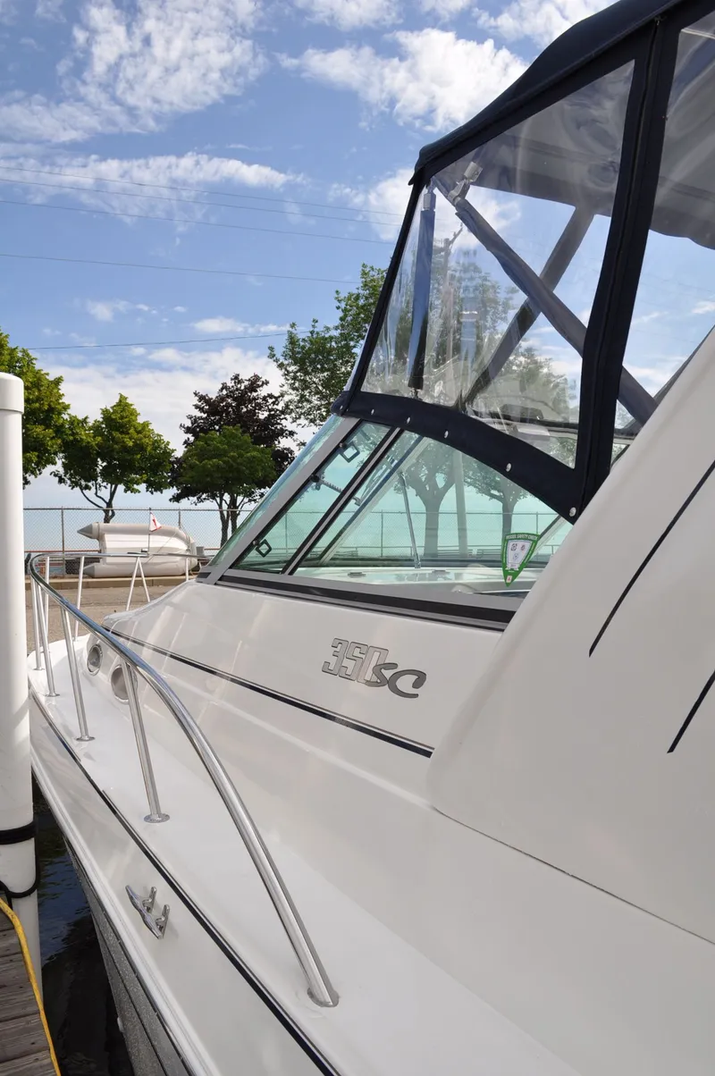 Slide: The Image of A white boat with a black canopy docked. Trees and blue sky in the background. - 5