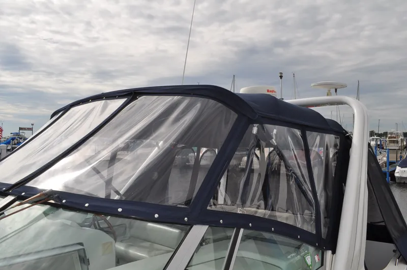 Slide: The Image of A 1999 Doral 350sc with a blue canopy and clear windows at the marina. - 27
