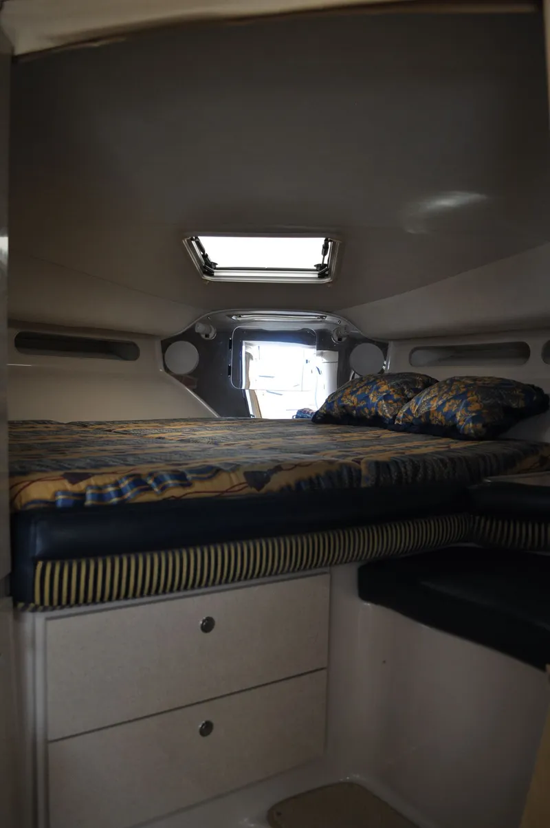 Slide: The Image of The cabin of the 1999 Doral 350sc features a cozy bed with pillows and storage underneath. - 16