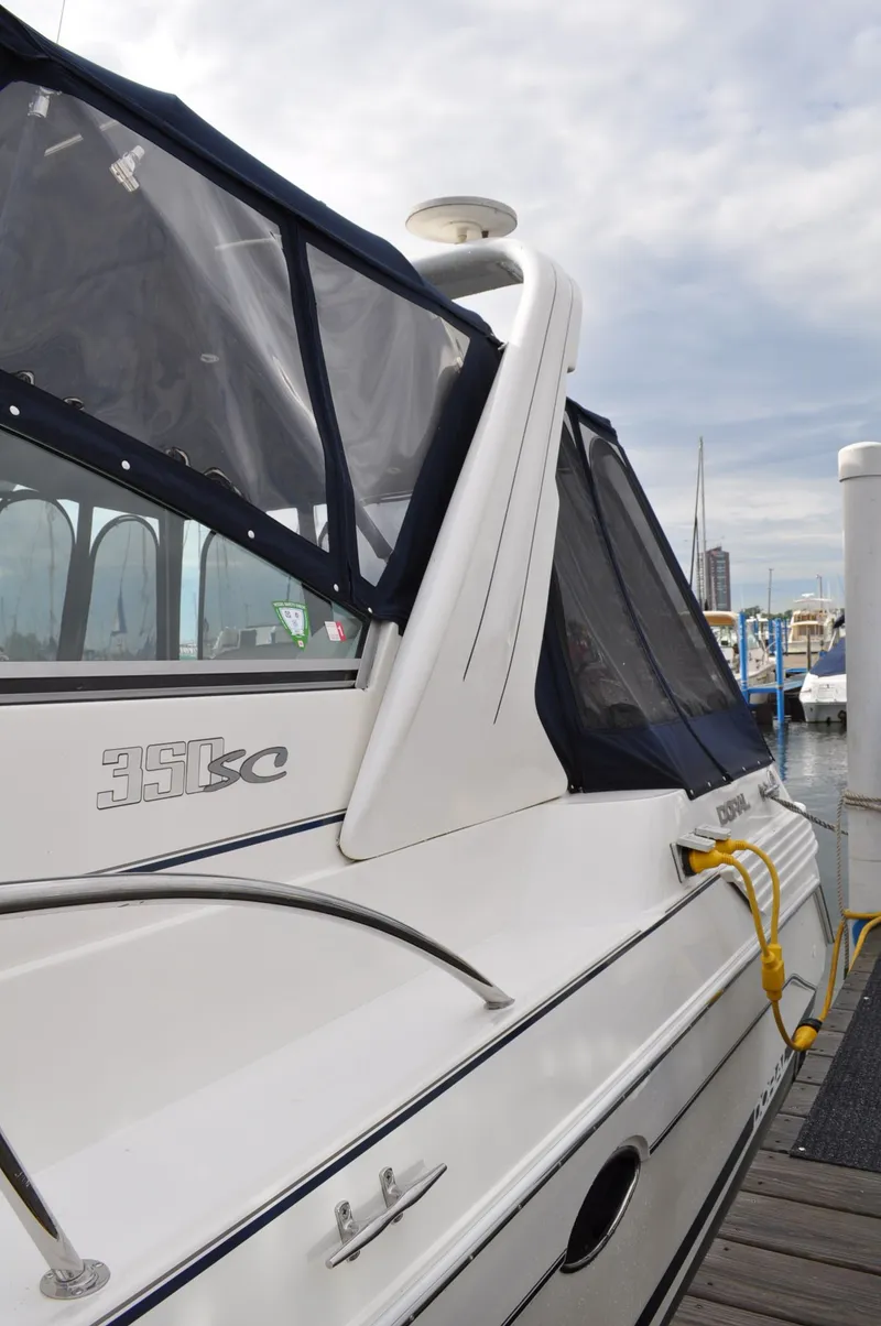 Slide: The Image of A 1999 Doral 350sc boat docked. It features a white deck and black covers. - 4