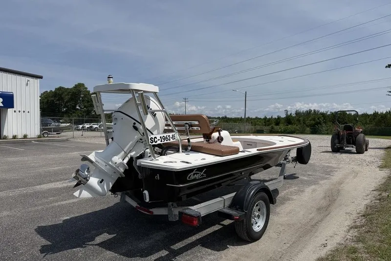 Slide: The Image of 2012 Chaos 16 Bonefish boat on trailer, parked outdoors near a building and tractor. - 5
